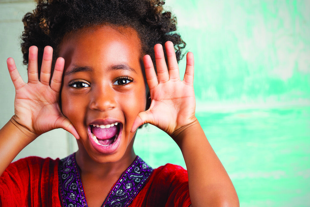 Joyful child framing face with hands