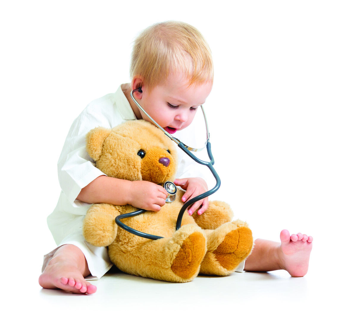Toddler in white shirt examining teddy bear with stethoscope
