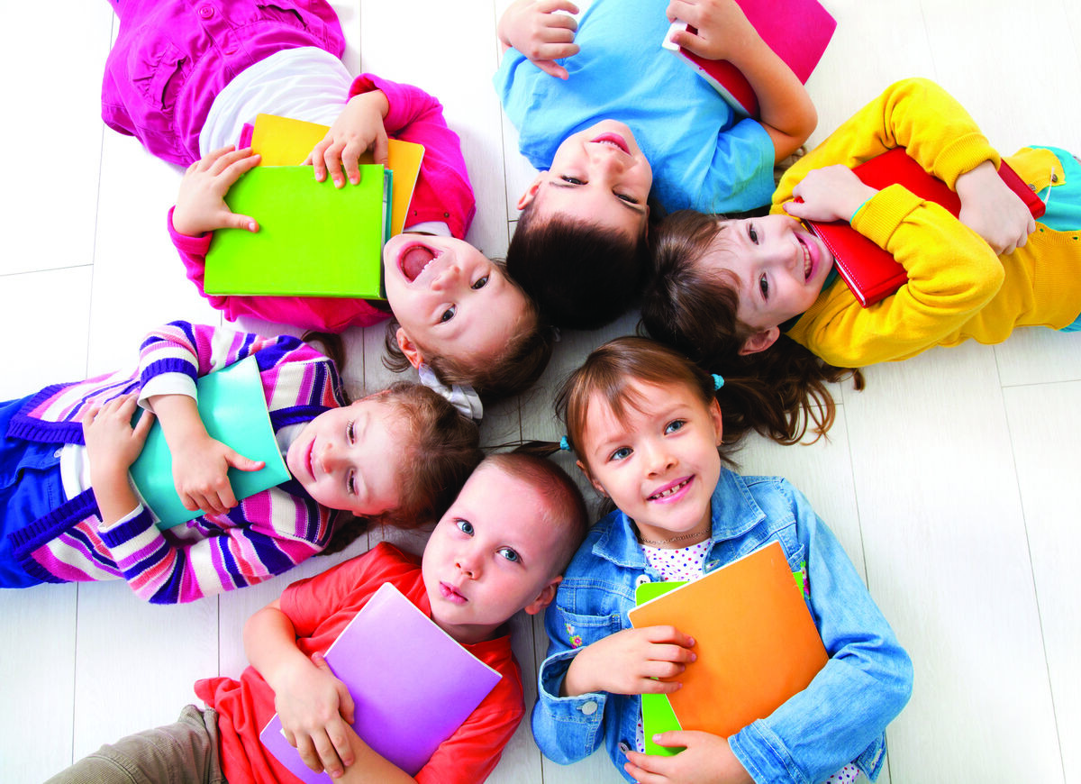 Children laying in a circle with books