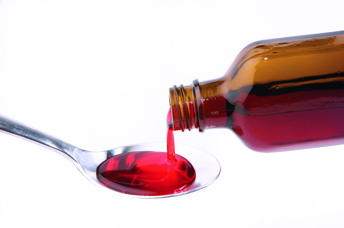 Liquid medication poured from bottle into spoon