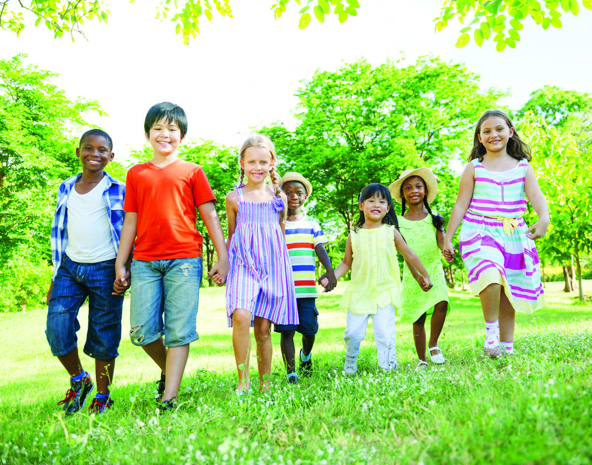 Diverse children walking through a park holding hands