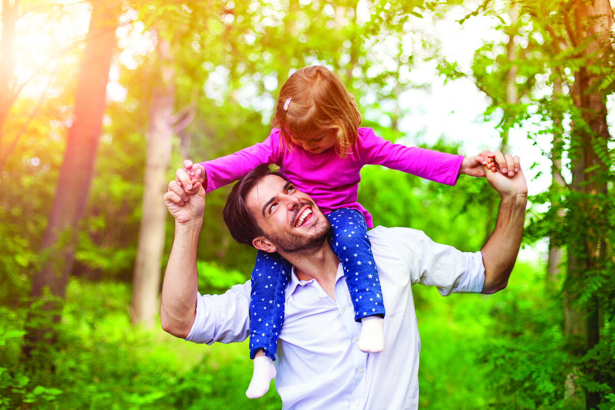 Father carrying daughter on shoulders outdoors