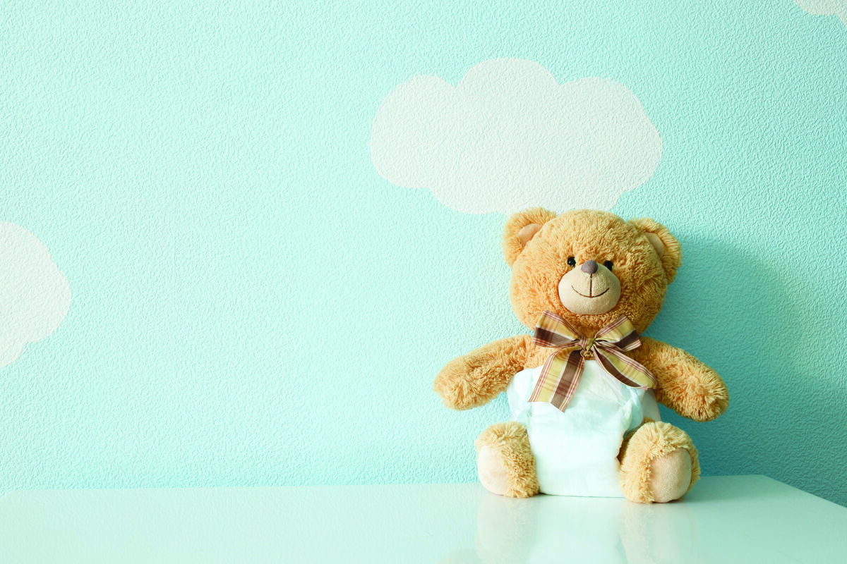 Teddy bear wearing a white diaper against blue wall