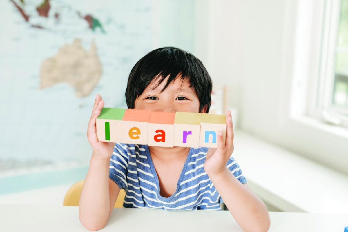 Boy holding letter blocks spelling learn