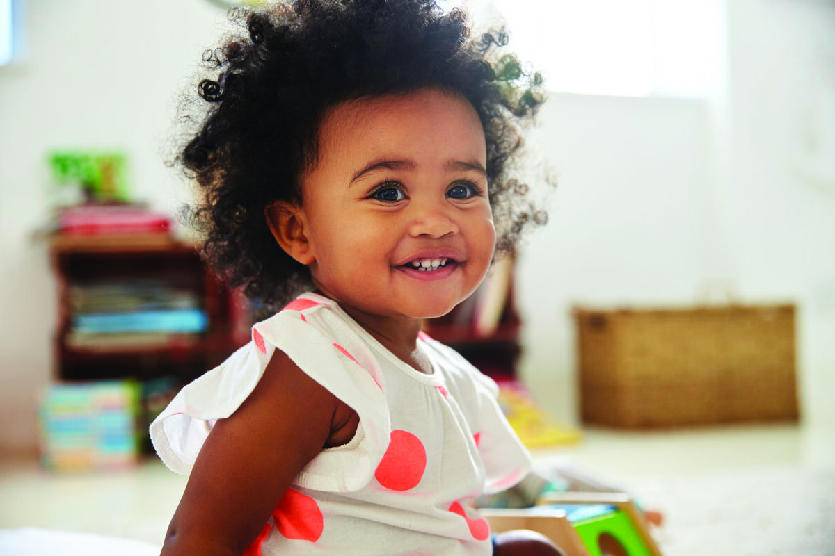 Smiling toddler in white polka-dot dress
