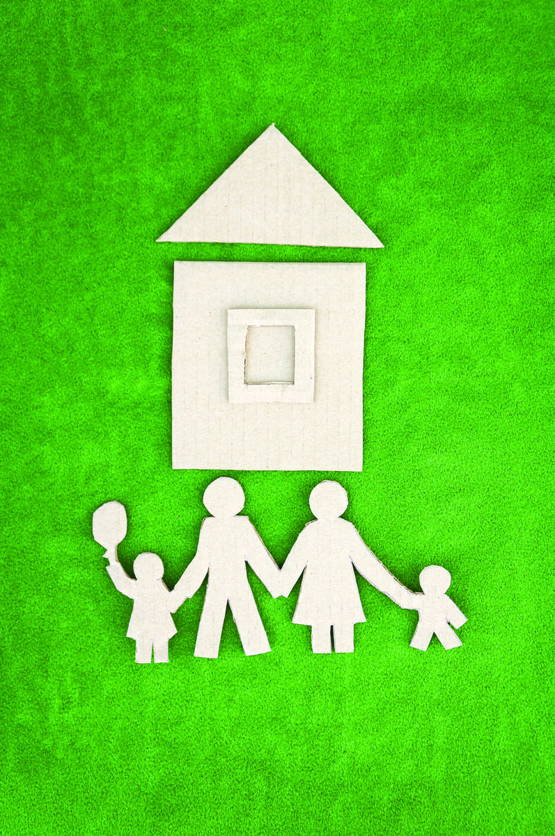 Paper cutout of family in front of house on green grass